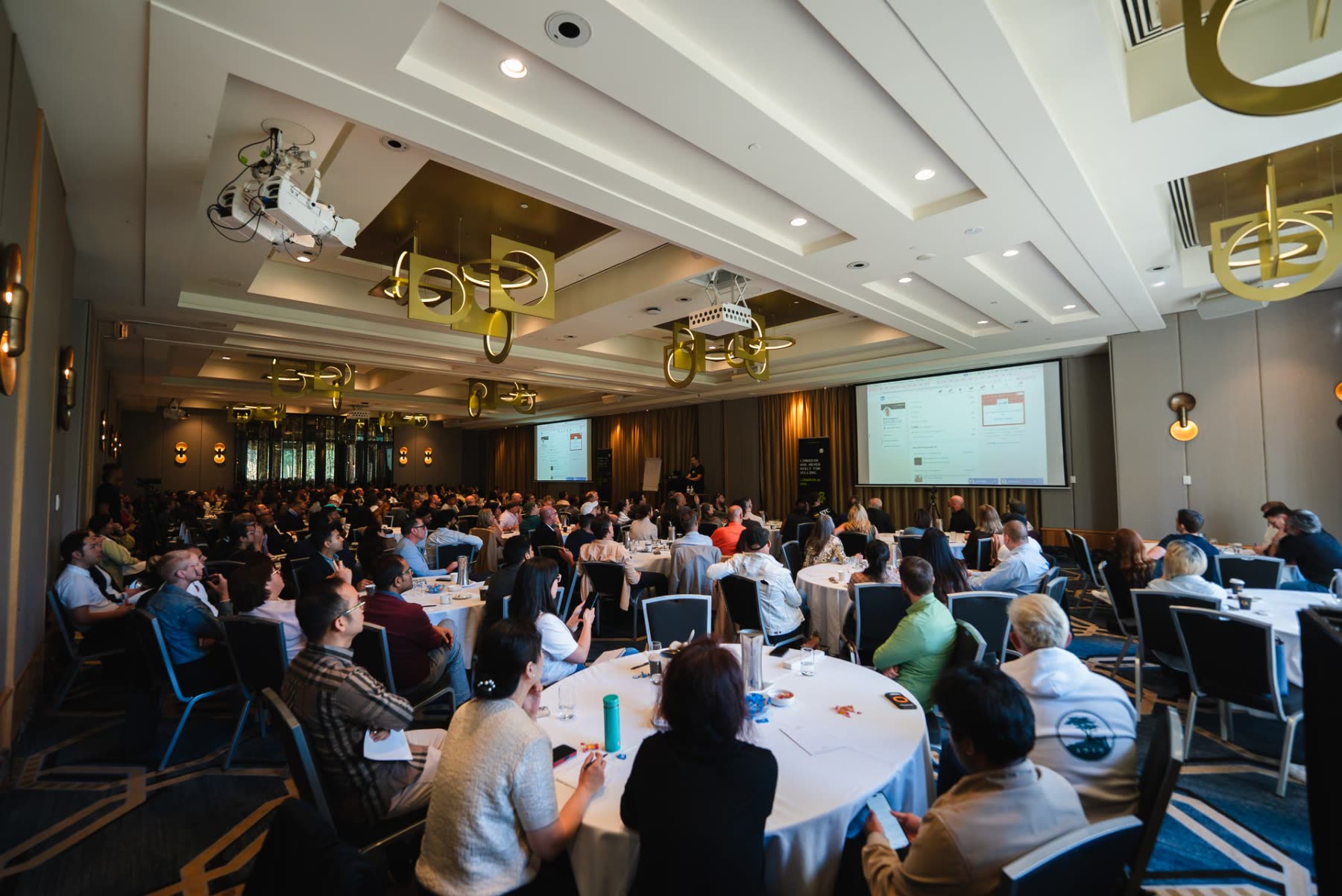 A full conference room of founders watching a keynote